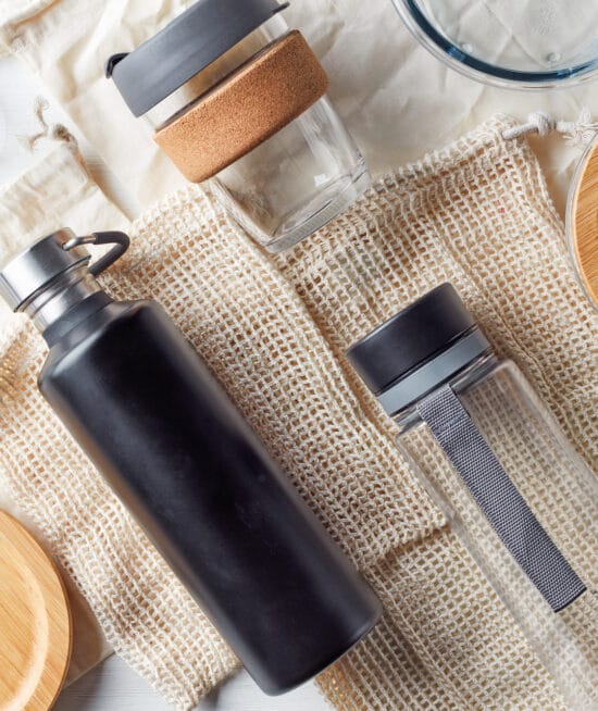Zero waste concept, water bottles, coffe cup, glass storage containers and cotton bags, from above - JSB Designs Earth Day tips